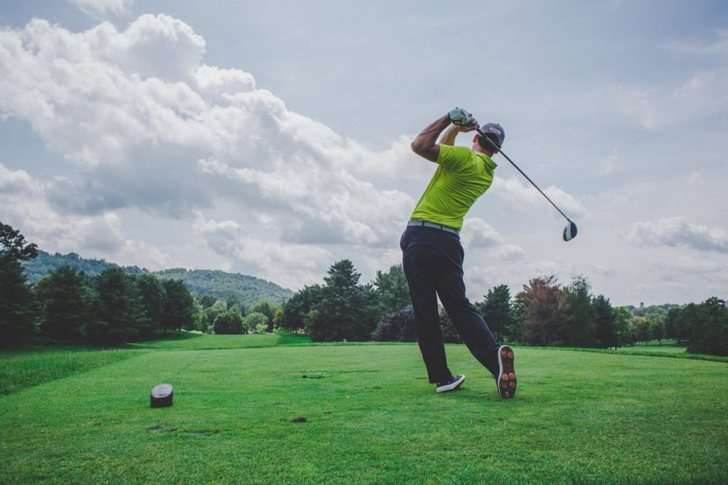 photo of man swinging golf driver